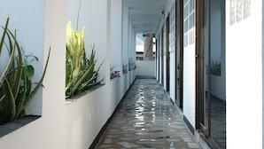 A corridor with patterned flooring, white walls, and potted plants. - Collection O Luna Hotel Pattaya (Pattaya)
