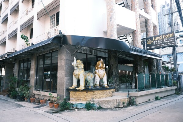 A hotel entrance with a black awning, two golden elephant statues, and a signboard.