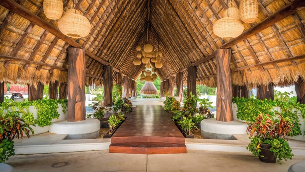 A covered walkway with a thatched roof, wooden pillars, and hanging wicker lamps. - Modern 3 BR Condo in PDC - Muuyal 304 (Playa del Carmen)