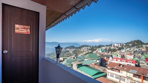 A view from a balcony overlooking a town with a wooden door labeled "Kansa" and a street lamp. - Monratino Himadrie (Darjeeling)