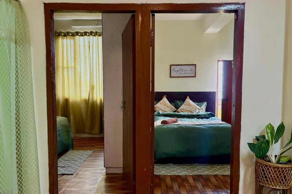 A bedroom with a bed, a bedside table, a wall-mounted sign, and a potted plant.