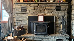 A stone fireplace with a framed certificate, a vintage radio, and decorative items. - Cozy Catskill Mountain Cabin (Margaretville)
