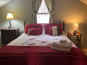 A neatly made bed with red bedding, a bedside table with a lamp, and a window with curtains. - Cozy Catskill Mountain Cabin (Margaretville)