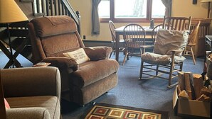 A cozy living room with a brown leather sofa, a rocking chair, and a patterned rug. - Cozy Catskill Mountain Cabin (Margaretville)