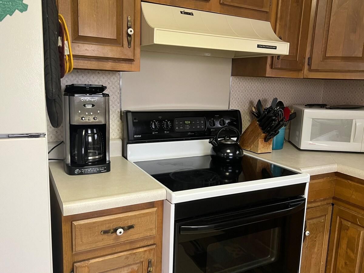A kitchen with a stove, microwave, coffee maker, and wooden cabinets.