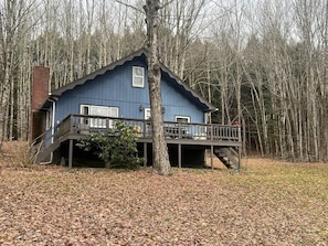 A blue cabin with a wooden deck and stairs, surrounded by trees. - Cozy Catskill Mountain Cabin (Margaretville)