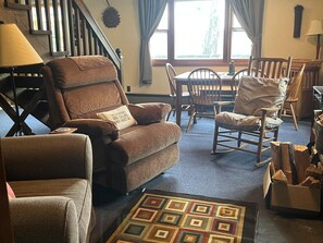 A cozy living room with a brown leather sofa, a rocking chair, and a patterned rug. - Cozy Catskill Mountain Cabin (Margaretville)