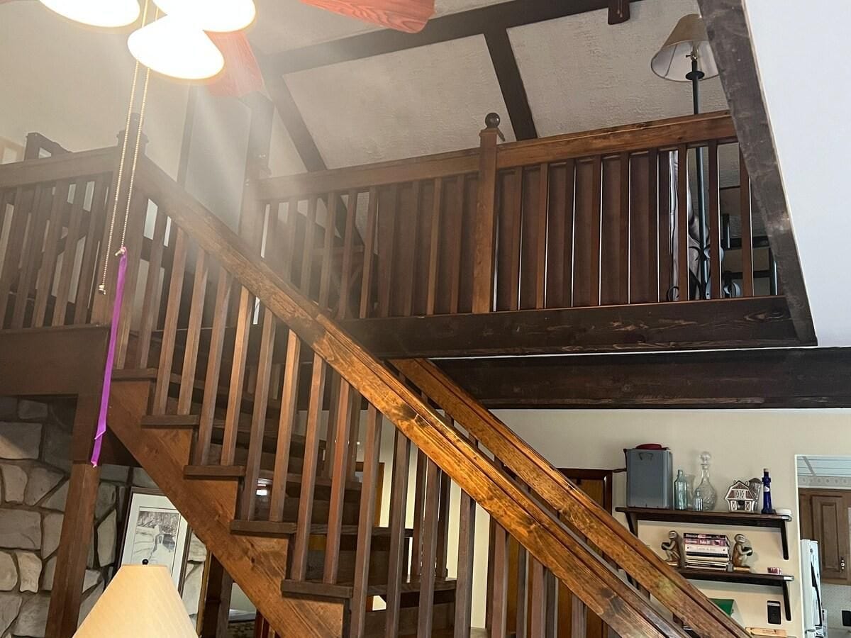 A wooden staircase with a stone wall background, a lamp, and a shelf with various items.