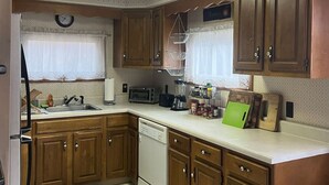 A compact kitchen with wooden cabinets, a dishwasher, a toaster, and a spice rack. - Cozy Catskill Mountain Cabin (Margaretville)