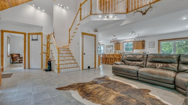 Ett rymligt vardagsrum med en lädersoffa, en stor matta och en trappa som leder upp till ett övre plan.