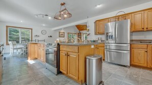 A modern kitchen with wooden cabinets, stainless steel appliances, and a central island. - Pet-Friendly Maine Retreat | Private Heated Indoor Pool, Fenced Yard, 17 Acres, ATV Trails & Lake Access Near Roberts Pond (Lyman)