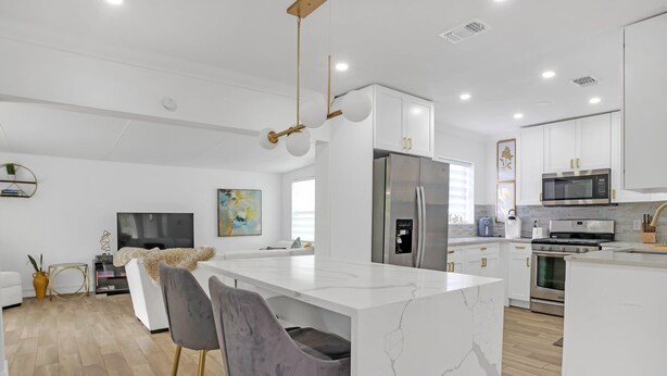 Une cuisine moderne avec des meubles blancs, un îlot central et des appareils électroménagers en acier inoxydable.