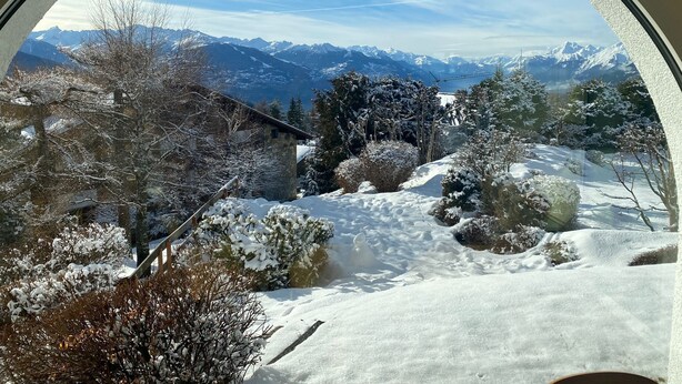 Un paysage montagneux enneigé avec un bâtiment en pierre et des arbres.