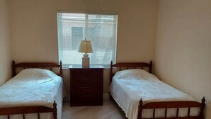 A bedroom with two wooden beds, a ceiling fan, and a window with blinds.