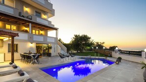 A modern outdoor pool area with a dining setup and lounge chairs.