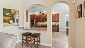 A modern kitchen with wooden cabinets, a granite countertop, and a ceiling fan.