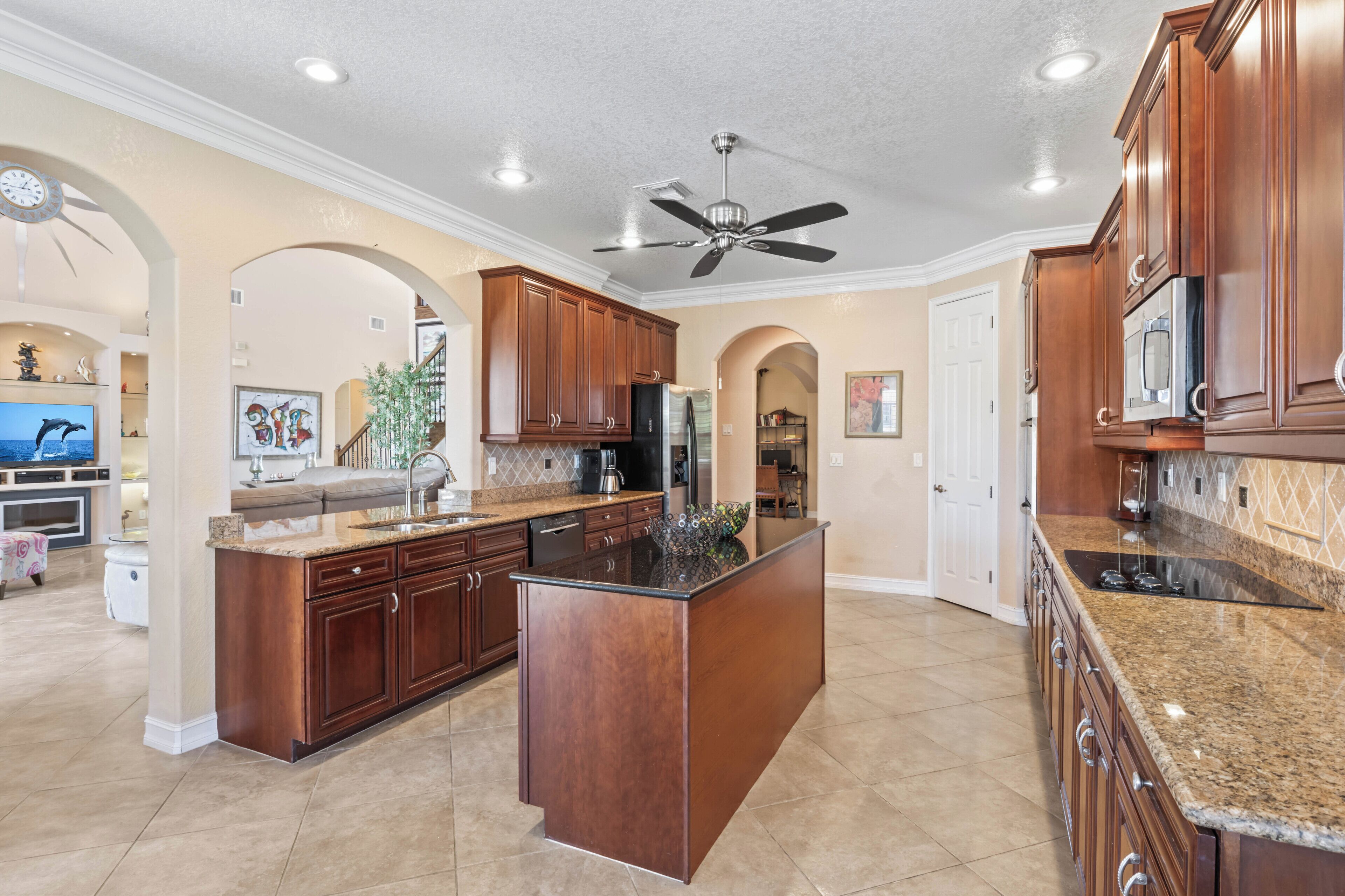 A spacious kitchen with dark wood cabinets, a granite countertop, and a central island.
