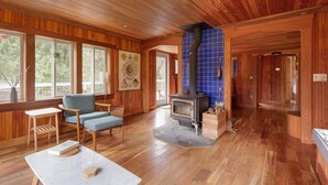 A wooden interior with a fireplace, large windows, and a cozy seating area. - Sweet Root Hollow - 12 Private Acres on Farmer Creek (Cloverdale)