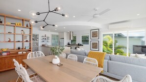 A modern living space with a dining area, kitchen, and a large window with a view of greenery.