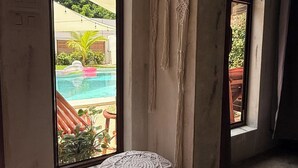 A room with large windows, a macrame wall hanging, and a round macrame stool.