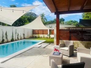 Relax by the pool surrounded by lush greenery and comfortable wicker furniture.