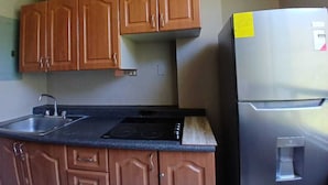Una cocina con armarios de madera, un refrigerador de acero inoxidable, un fregadero y una estufa.