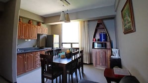Una cocina compacta con armarios de madera, una mesa de comedor con sillas y un microondas.