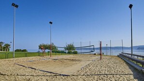 Un terrain de beach-volley avec un filet, des projecteurs et des bancs.