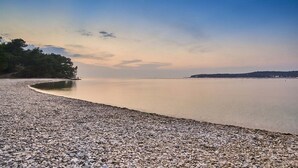 Une plage de galets avec une eau calme et un ciel dégagé.