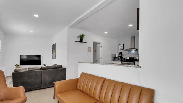 Una sala de estar moderna con un sofá de cuero marrón, un sofá gris oscuro y un televisor.