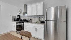 Una cocina moderna con armarios blancos, electrodomésticos de acero inoxidable y una silla de madera.
