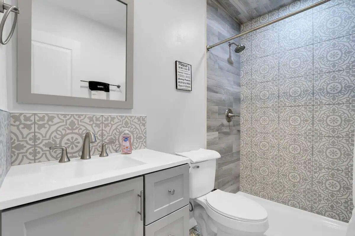 Une salle de bain avec un lavabo blanc, trois robinets, des toilettes et un espace douche.