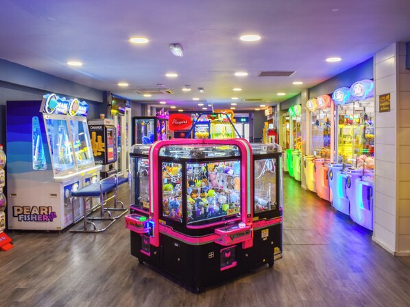 An indoor arcade with claw machines and a 'Pearl Fishery' game.