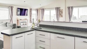 Una cocina moderna con armarios blancos, encimera de granito y comedor con sofá y mesa.