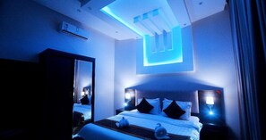 Moderni hotellihuone, jossa on suuri sänky, yöpöytävalaisimet, kattovalaisin ja peili.