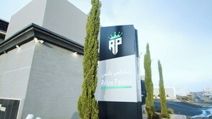 Schild für 'Relax Palace' mit einem Kronen-Logo, das ein Hotel oder Resort kennzeichnet.