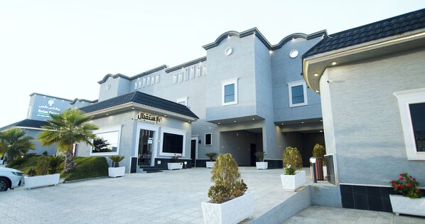 A modern hotel with a large entrance, outdoor seating, and landscaped areas. - Relax Palace for Hotel Villas (Abha)