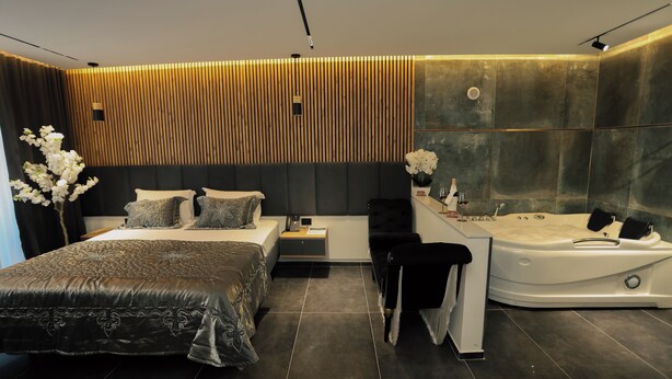 Une chambre moderne avec un grand lit, une coiffeuse avec baignoire et un mur recouvert de panneaux en bois.