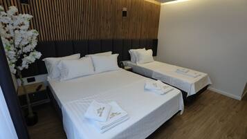 A hotel room with two beds, wooden paneling on the wall, a nightstand with a lamp, and a potted plant.