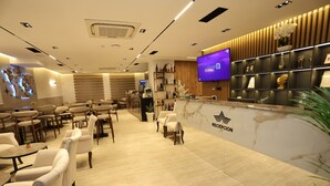 Un espace d’accueil doté d’un comptoir en marbre, d’un téléviseur et d’un bureau de réception.