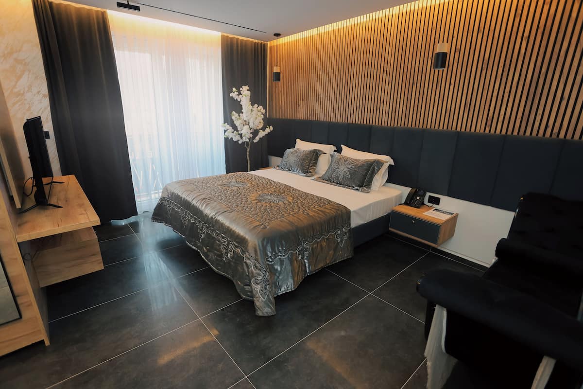 A modern bedroom with a large bed, a bedside table, a nightstand, and a chair.