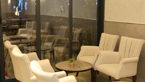 Un espace lounge moderne, doté de fauteuils en cuir et de tables rondes, avec un mur en verre qui reflète l’intérieur.