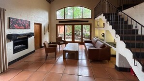 A spacious living area with a fireplace, comfortable seating, and a staircase leading to an upper level.