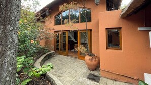 A two-story house with a curved roof, large windows, and a stone pathway leading to the entrance.