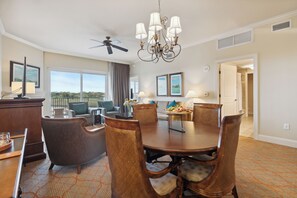 A dining area with a round table, chairs, and a chandelier. There is a ceiling fan, a window with a view, and a door leading to another room. - Marina Inn Grande Dunes Condos & Suites (Myrtle Beach)