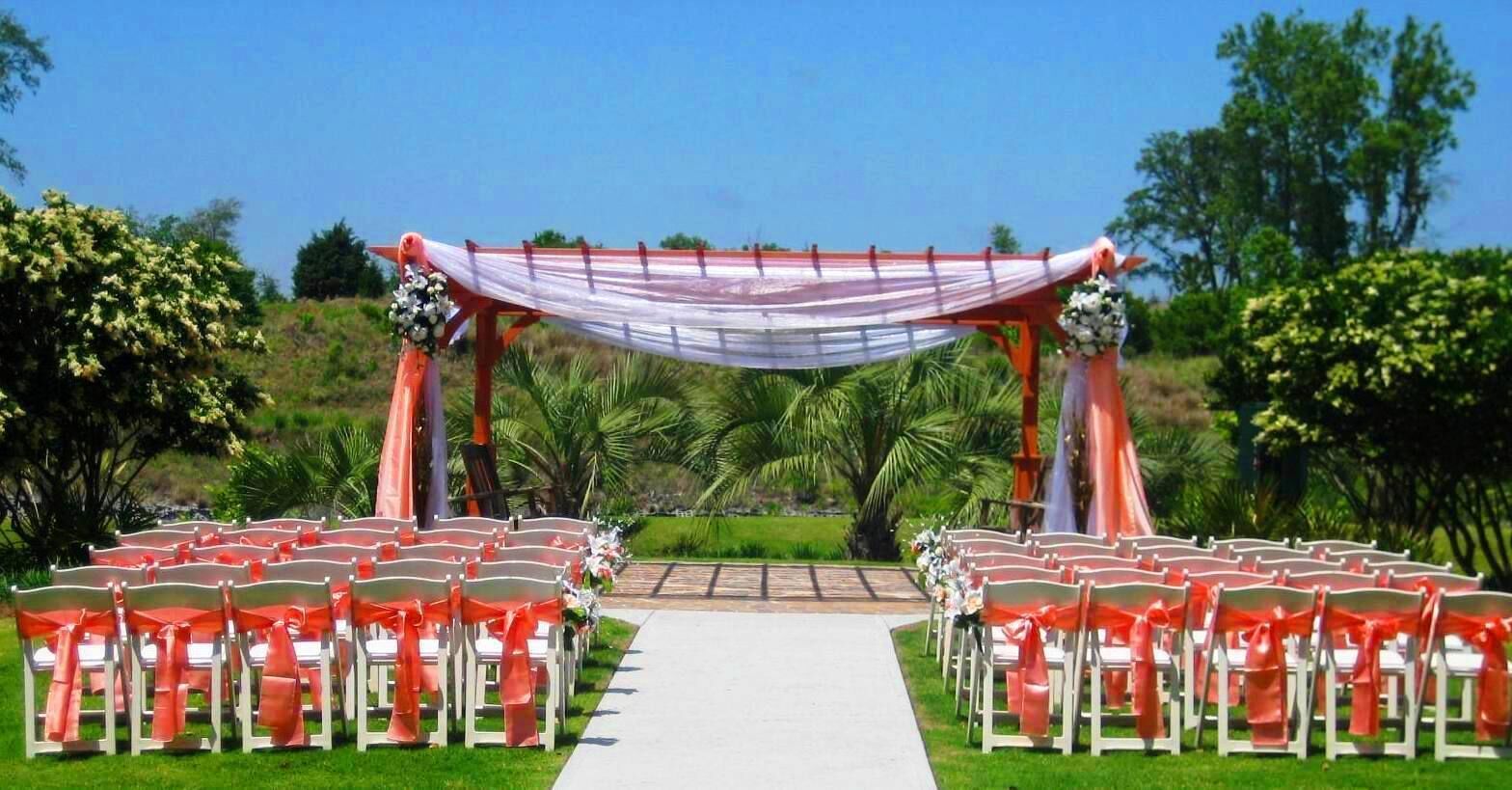 An outdoor wedding ceremony setup with white chairs and a canopy.