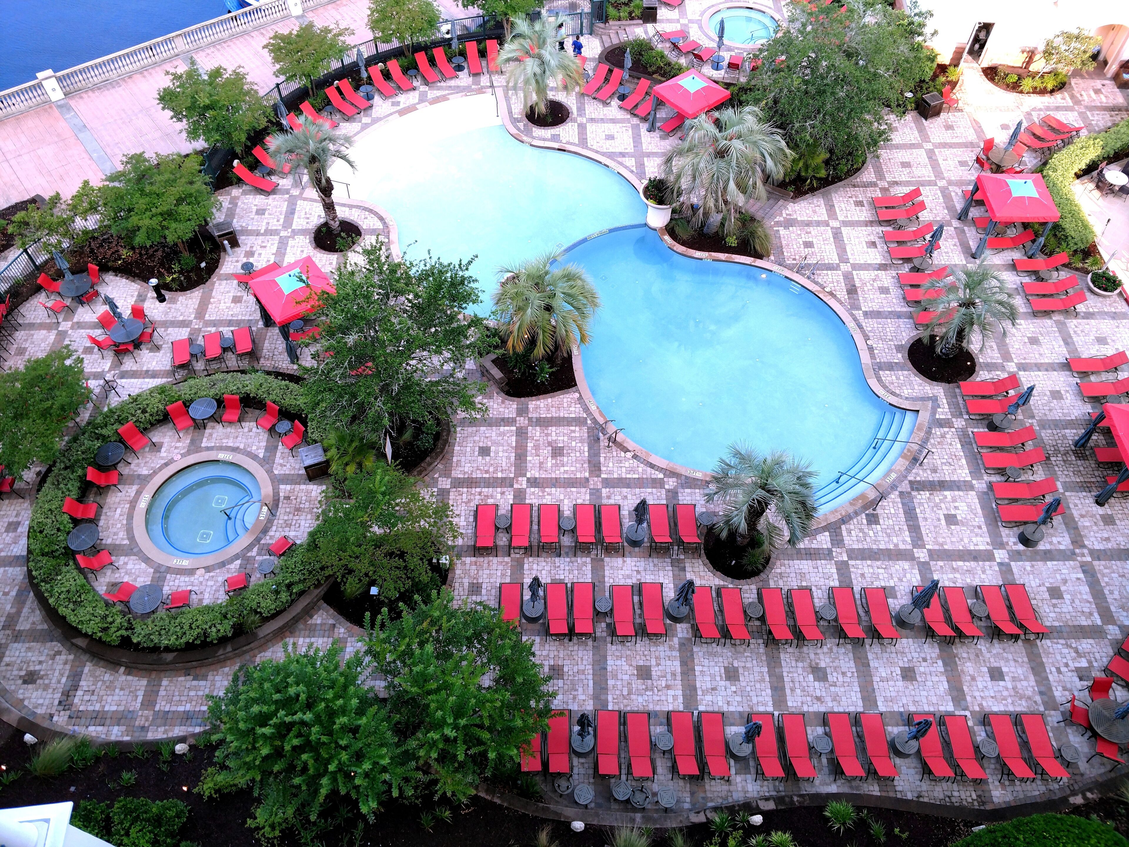 Zona de piscina con múltiples tumbonas y una piscina central.