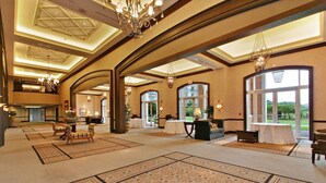 A spacious lobby with high ceilings, chandeliers, and large windows offering views of the outdoors.