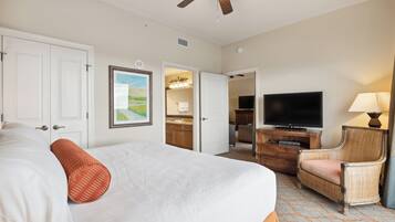 A hotel room with a large bed, a television, a chair, and a ceiling fan.