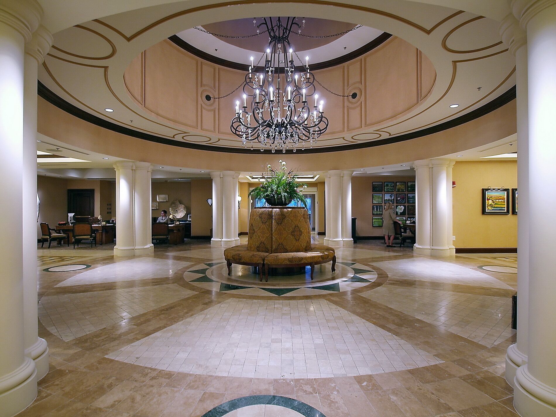 A spacious lobby with a central seating area, a chandelier, and a reception desk.